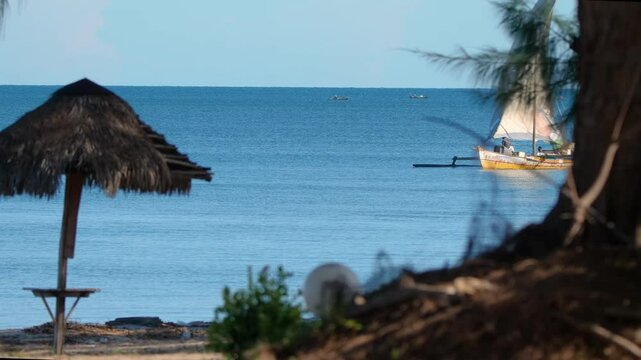 4K footage captured from the beach of a colorful traditional dhow sailing by wind in the Indian Ocean, Mozambique Channel, north-west Madagascar, vibrant sails and stunning ocean views in Background