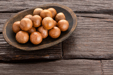 Macadamia integrifolia - Macadamia nuts in bowl on wooden background.