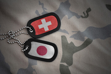 vintage army blank, dog tag with flag of switzerland and japan on the khaki texture background....