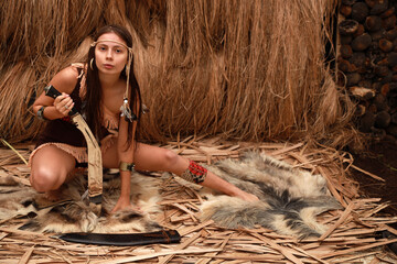 Young beautiful native American woman sitting on the animal skin and holding huge kukri knife
