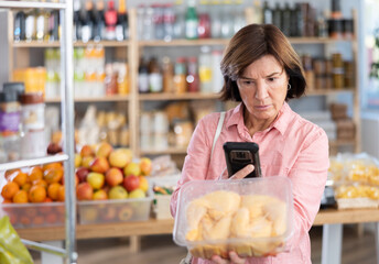 Female purchaser scanning QR code or barcode of chicken thighs in supermarket