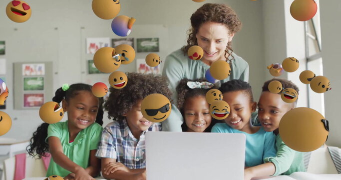 Image of emoji icons over diverse schoolchildren and teacher using laptop - Powered by Adobe
