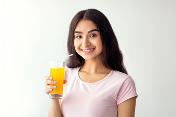 Pretty Indian woman drinking fresh fruit juice, enjoying detox beverage at home, copy space. Slim Eastern lady having tasty drink indoors. Healthy living and wellbeing concept