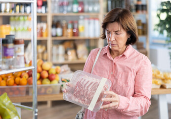 Female customer chooses a pork loin in the produce section of a supermarket