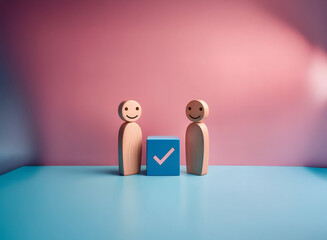 Two smiling wooden figures stand beside a blue square with a checkmark, symbolizing agreement, collaboration, or a task completed.  The scene is set against a pink and blue background.