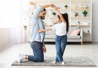 Loving arabic father dancing with his adorable little daughter at home, happy dad teaching pretty long-haired female kid dancing waltz, single father spending weekend with his child, copy space