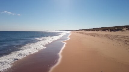 Fototapeta premium Waves retreating from a sandy beach, leaving a glossy sunlit surface.