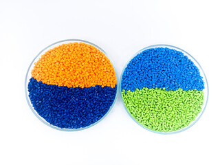 Red, blue masterbatch granules in glass cup, polymer carrying pigment with chips poured in white...