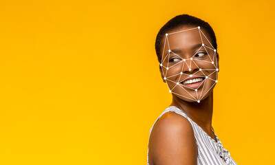 A young woman with a joyful expression turns her head slightly to the side against a vibrant yellow backdrop. Facial recognition points are superimposed on her face, illustrating modern technology.