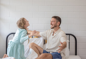 Obraz premium Father and daughter share a joyful moment while cuddling in a cozy bedroom on a sunny morning