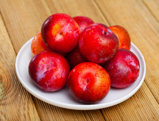 Tasty ripe red plum on a wooden surface. Healthy fruits