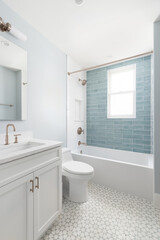 A bathroom with a white vanity cabinet, white marble countertop, and a shower with white and light blue subway tiles. No brands or labels.