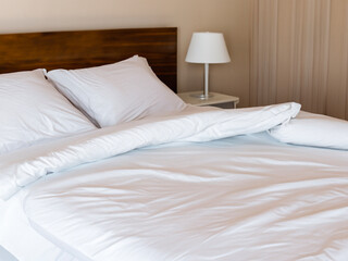 the bed is messy with white pillows and sheets