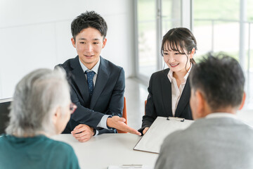 Fototapeta premium シニア夫婦に書類の説明をするビジネスウーマンとビジネスマン 