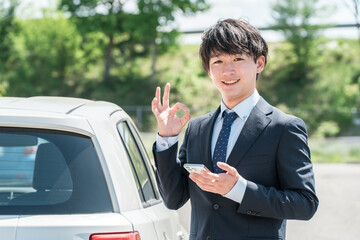 車の査定をするカーディーラの査定士・営業マンの若いアジア人男性
