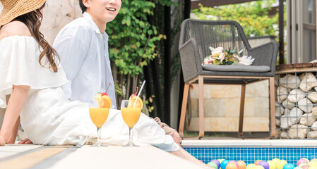 旅行先のリゾートホテルのプールサイドで遊ぶカップル・夫婦  © buritora