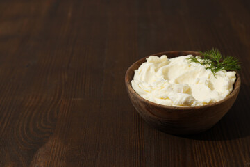 Philadelphia cheese in a wooden plate on a brown background.