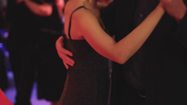 Couples dancing traditional latin argentinian dance milonga in the ballroom, tango salsa bachata kizomba lesson in red and purple lights, evening dance school class festival, performance rehearsal
