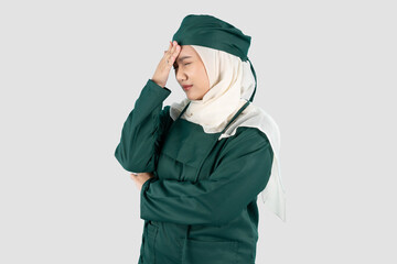 portrait of a female doctor wearing green surgical holding his head while looking dizzy