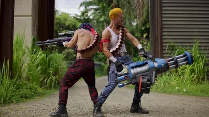 Epic slow motion of two muscular soldiers pretending to shoot large, sci-fi weapons in jungle area - dolly in