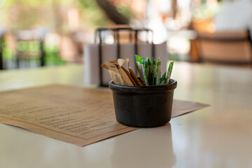 Beautiful black bowl for salt, sugar for food, next to the menu over the table of an open area restaurant.