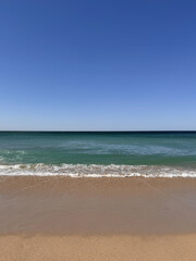 water on sandy beach with clear blue sky on a sunny day