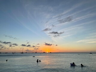 Fototapeta premium Sunset over a serene beach with silhouetted figures