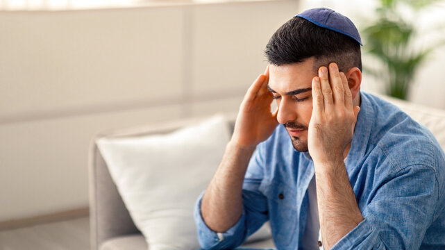 Sad tired young man touching and massaging his temples having headache migraine or depression, upset frustrated guy troubled with problem feeling stressed suffer from grief, sorrow concept