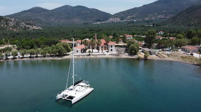 Luxury yacht sailing at seaport with Zaira hotel estate in background surrounded with olive trees garden and mountains, Mytilene, Lesvos Island, Aerial view