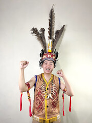 Cheerful and happy young man posing wearing traditional Dayak clothes isolated on white background