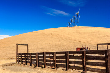 A fence surrounds a field with a windmill in the background