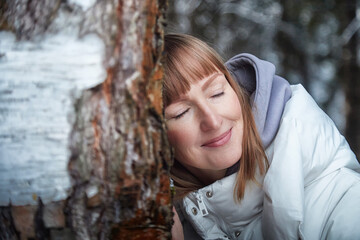 Winter wonderland stroll brings joy to a middle-aged woman in the snowy forest celebrating New Year