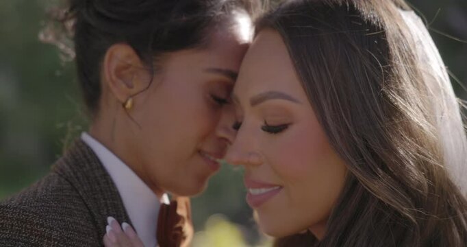 Closeup of two diverse woman, vibrant multiethnic lesbian wedding, showcasing the deep love between two young Indian and Asian women touching each other forehead with eyes closed and smiling