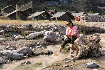 Mature woman fishing in river during summer.