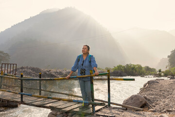 Senior woman standing with binoculars on an observation deck in a wildlife reserve