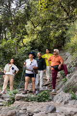 Group of happy seniors backpackers hiking during spring day in nature.