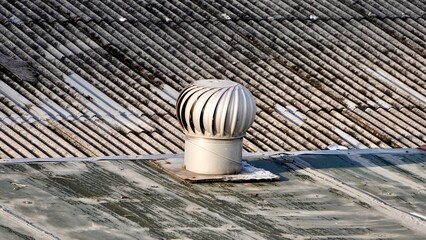 Round metal turbine ventilator system building exterior object isolated on horizontal asbestos roof background. © Amanda Alamsyah