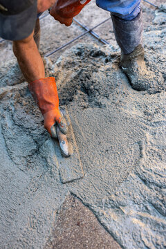 Construction worker smoothing wet concrete with a hand trowel