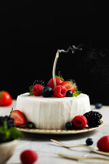 Small cake with cream cheese cream with a golden smoking candle. Bento cake decorated with fresh berries and frosting on a beige ceramic plate. Birthday dessert. Copy space