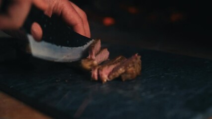 A close-up of a chef slicing a juicy steak on a cutting board in warm, moody lighting