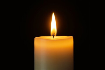 Candle with a bright flame glowing in darkness.