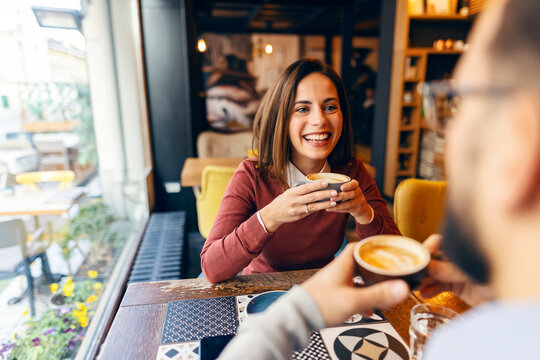 Portrait of flirty woman having coffee with her blind date partner in coffee shop.