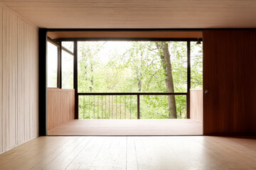 Modern minimalist interior with large windows overlooking lush greenery in a quiet setting