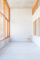 Obraz premium Bright empty interior with large windows and a wooden chair in a minimalist setting