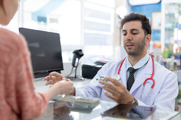 Fototapeta premium Male pharmacist medicine giving to customer pharmaceutical healthcare prescription at counter pharmacy clinic dispensary. Doctor service buying patient in drug store.
