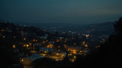 Obraz premium Nightfall over City Hillsides: A Panoramic View of Illuminated Houses and Distant Lights