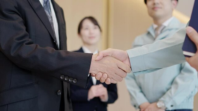 握手をするビジネスマンと作業服を着た男性