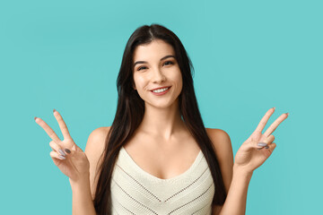 Young woman showing peace sign on blue background