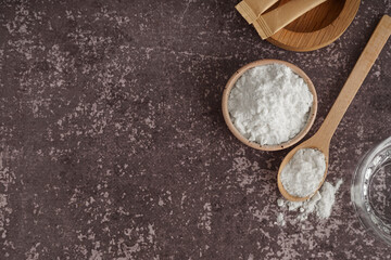 Bowl and spoon with collagen powder on grey grunge background