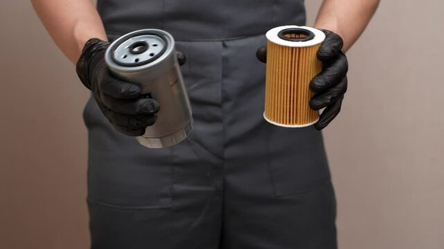 Auto mechanic holding car filters: oil and fuel filters, close-up. Car maintenance concept, auto parts replacement. 